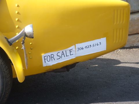 1971 Ford Ranchero - A yellow vehicle is seen from the rear, displaying a "FOR SALE" sign with a contact phone number.