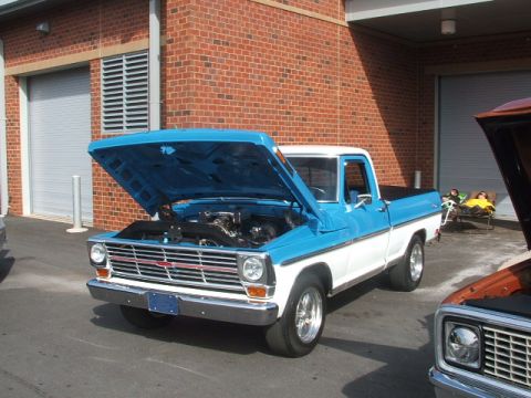 1971 Ford Ranchero - A blue and white pickup truck is parked with its hood open, showing the engine bay.