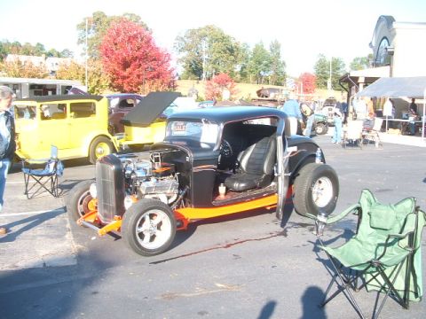 1971 Ford Ranchero - A custom hot rod coupe with its engine exposed is parked at an outdoor event, with other vehicles visible in the background.