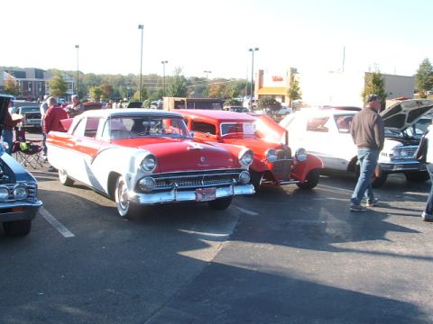 1971 Ford Ranchero - A red and white 1956 Ford Fairlane Crown Victoria is parked at an outdoor car show with other vehicles.