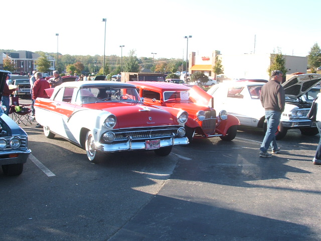 Red and white 1956 Ford Fairlane Crown Victoria parked at an outdoor car show