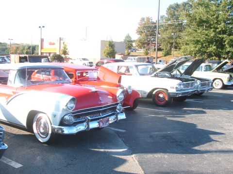 1971 Ford Ranchero - A red and white 1956 Ford Fairlane Crown Victoria is parked in a lot with other classic cars.