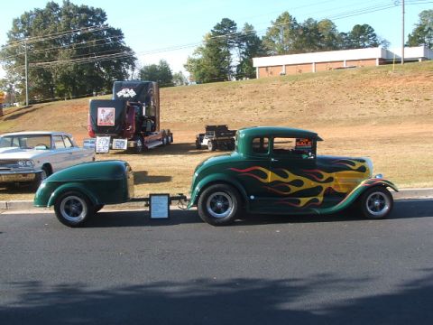1971 Ford Ranchero - A custom green coupe with flame decals is parked with a trailer, alongside other vehicles.