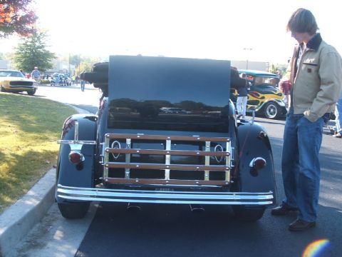 1971 Ford Ranchero - A person stands next to a vintage black pickup truck with a wooden bed at an outdoor car show.