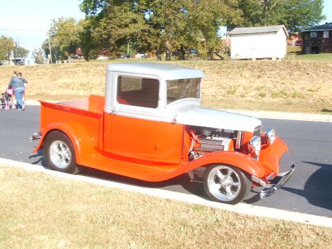 1971 Ford Ranchero - A customized vintage pickup truck is parked on the side of the road with a grassy embankment behind it.