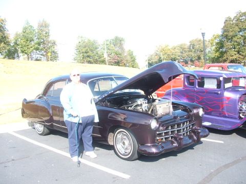 1971 Ford Ranchero - A person stands next to a dark purple coupe with its hood open, parked beside a purple hot rod with flame graphics.