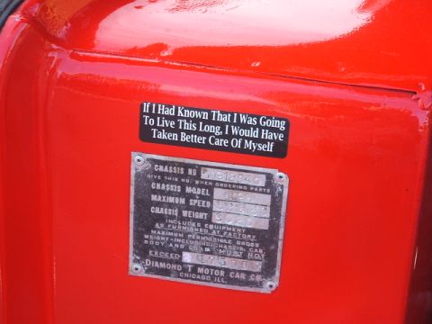1971 Ford Ranchero - A close-up view of a vehicle's identification plate and a humorous sticker affixed to its red painted surface.