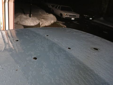2001 Ford Crown Victoria - A car hood with multiple holes is visible in the foreground, with two vehicles parked in the background.