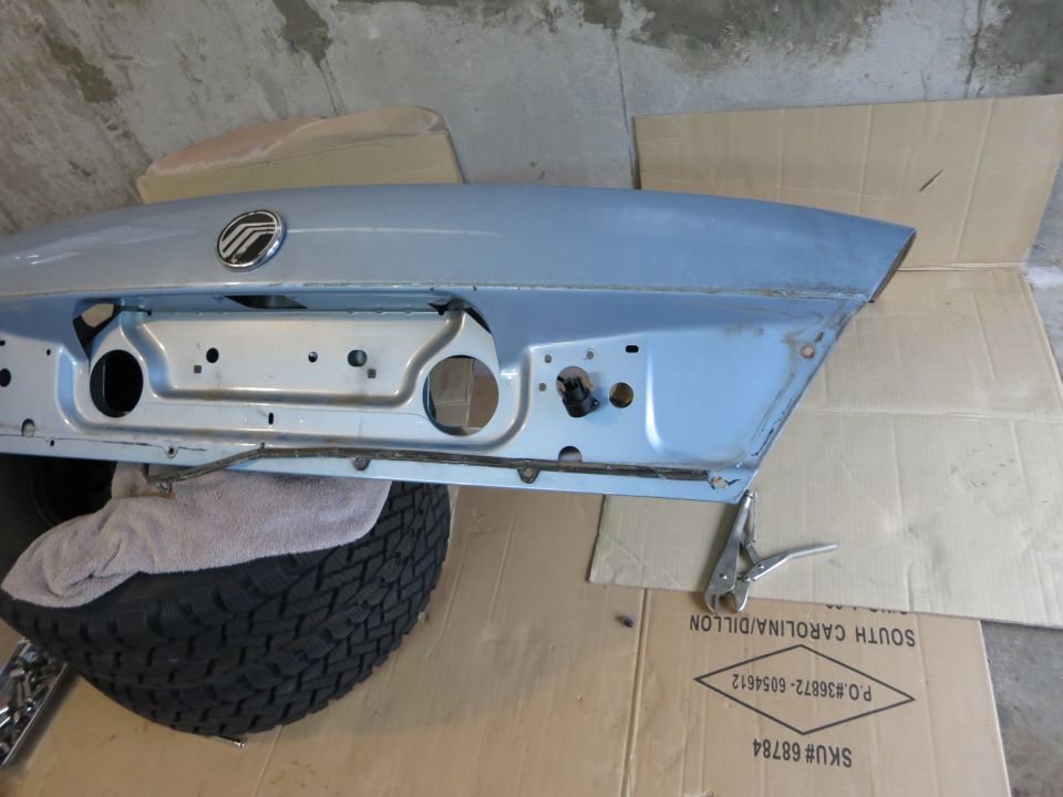 Light blue trunk lid with Mercury emblem, resting on a tire