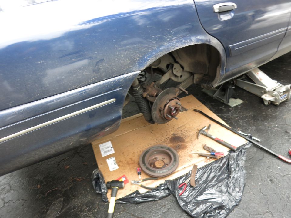 2001 Ford Crown Victoria rear brake assembly removed for repair, with tools on cardboard