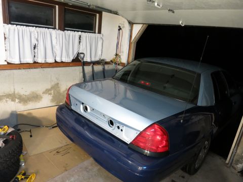 2001 Ford Crown Victoria - The rear of a Ford Crown Victoria is parked in a garage, showing its taillights and unpainted trunk lid.