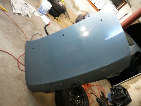 2001 Ford Crown Victoria - A light blue car trunk lid is shown with scuffs and mounting holes, resting on a tire.