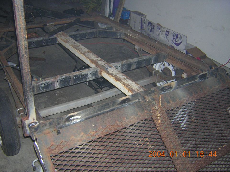 Trailer frame with diamond plate ramp, showing rust and welds