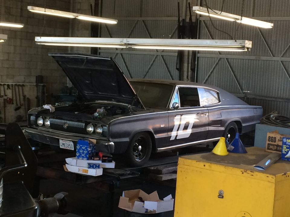 Dark gray 1967 Dodge Charger with a white number 10 on the side, hood up, in a garage