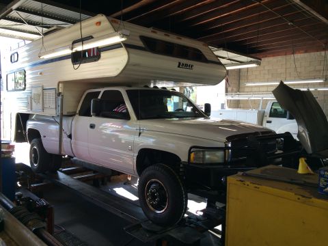 1997 Dodge 3500 - White 1997 Dodge 3500 pickup truck with a Lance camper shell is shown on a lift in a service bay.