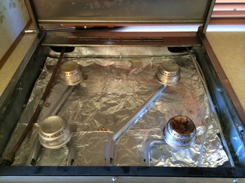 1997 Dodge 3500 - The interior of a stove top, four burners covered with aluminum foil for protection.