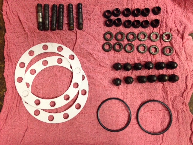 Engine parts kit with studs, gaskets, nuts, and O-rings on a pink cloth