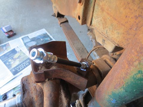 1946 Jeep Willys - A new brake line is connected to a rusty component of a vehicle's suspension system.