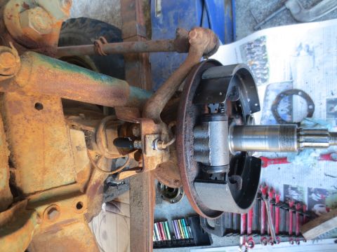 1946 Jeep Willys - Close-up view of a vehicle's wheel cylinder and brake assembly, showing rusty suspension parts and tools laid out nearby.