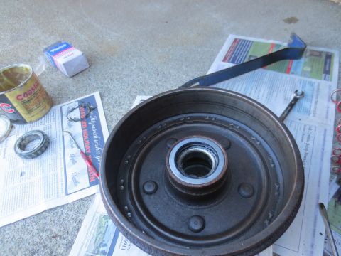1946 Jeep Willys - Brake drum assembly with bearing, grease, and tools laid out on newspaper.