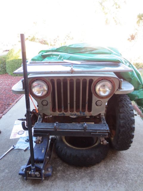1946 Jeep Willys - Front view of a 1946 Jeep CJ5 undergoing maintenance, supported by a jack.