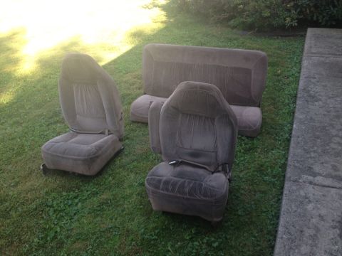 1993 Ford Bronco - Car seats and a bench seat are laid out on the grass.