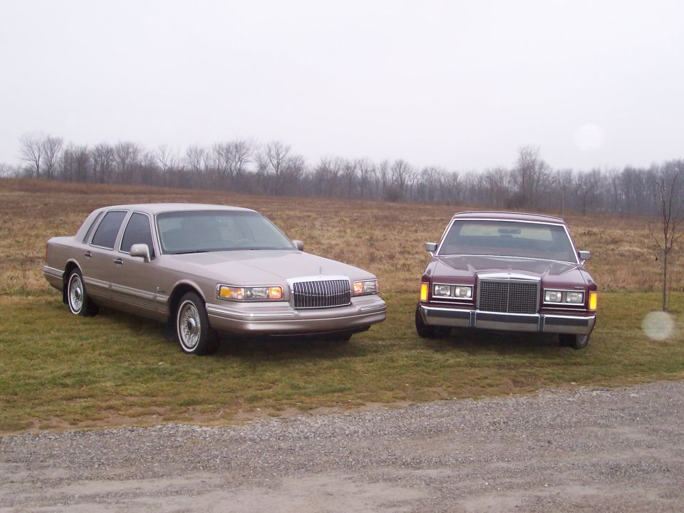 Tan and maroon Lincoln Town Car sedans parked in a field