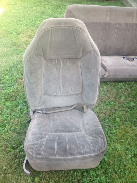 1993 Ford Bronco - Car seats removed from a vehicle and placed on the grass outdoors.