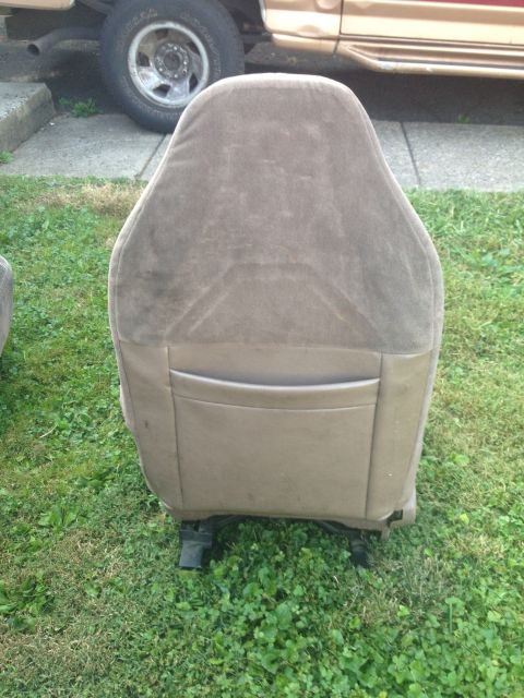 1993 Ford Bronco - A tan car seat is shown from the rear, with a gold vehicle visible behind it.
