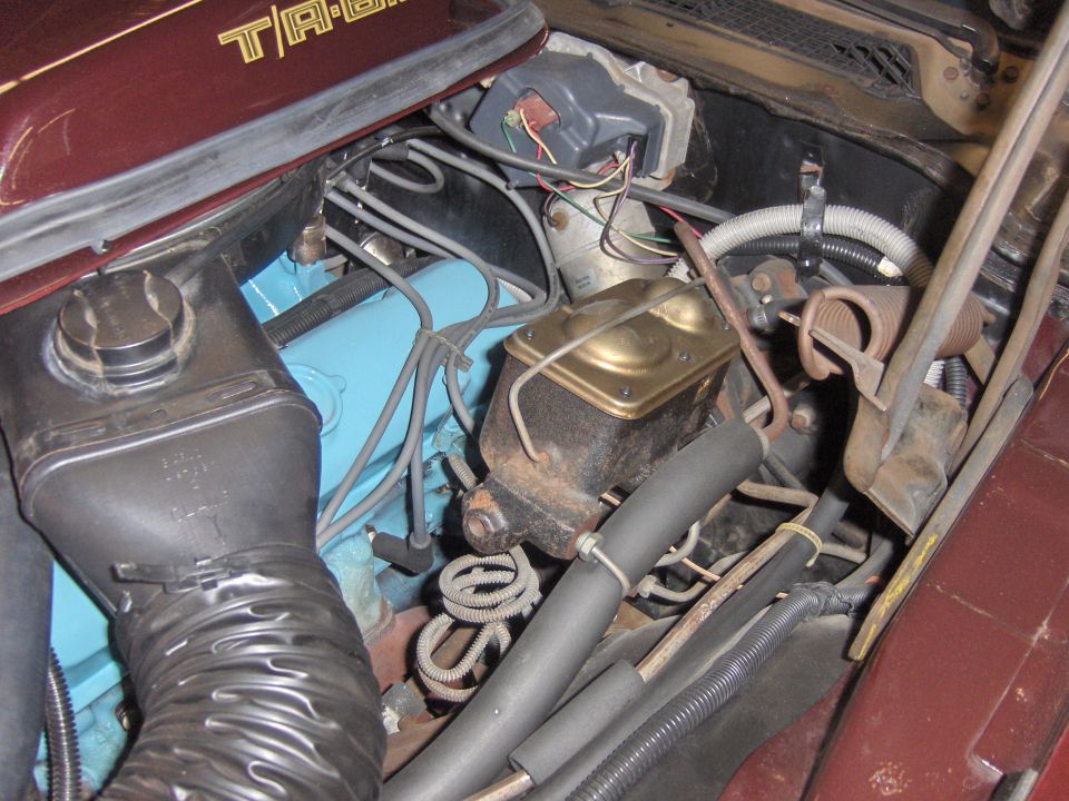 Engine bay detail showing brake master cylinder, blue engine block, and air intake hose