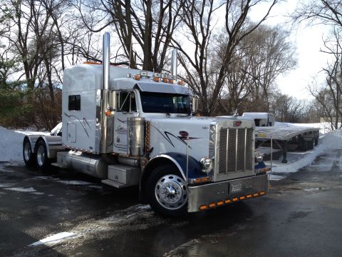 2003 Peterbilt 379 - A white Peterbilt 379 semi-truck is parked in a snowy lot with trees in the background.