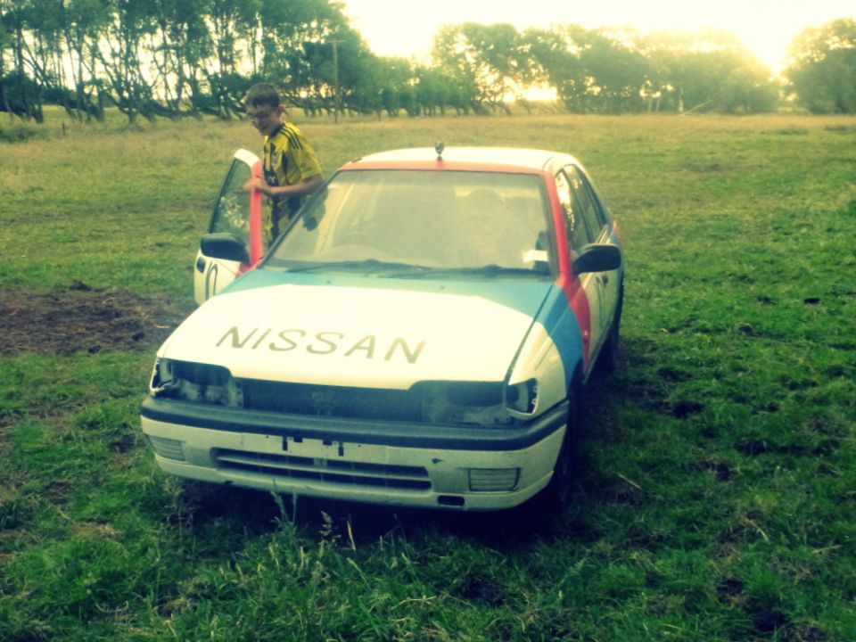 Nissan sedan with front damage, white with red and blue stripes, driver's door open