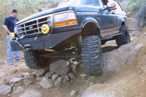 1994 Ford Bronco - A modified Ford Bronco tackles a challenging off-road course with large tires and an aftermarket bumper.