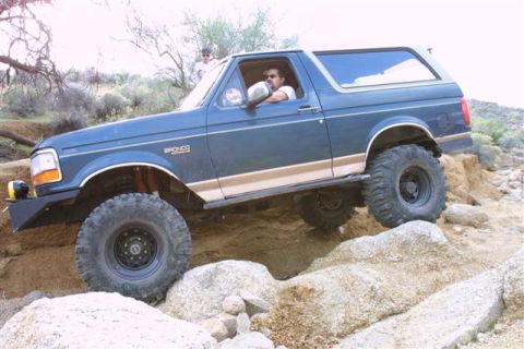 1994 Ford Bronco - Blue 1994 Ford Bronco tackles a challenging off-road course with large tires and a lifted suspension.