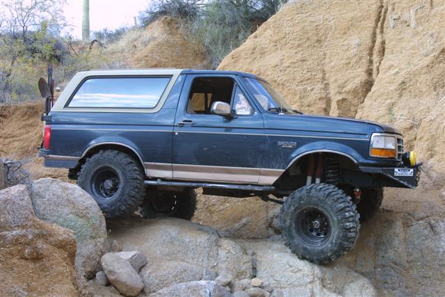 1994 Ford Bronco climbing over large rocks on a trail