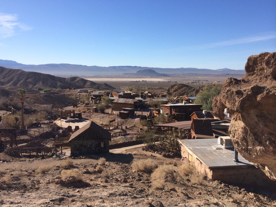 Desert town with old buildings and mountains in the background under a clear blue sky