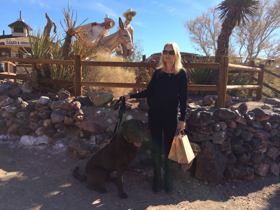 woman with dog in front of western statues and a building labeled Calico & Coss