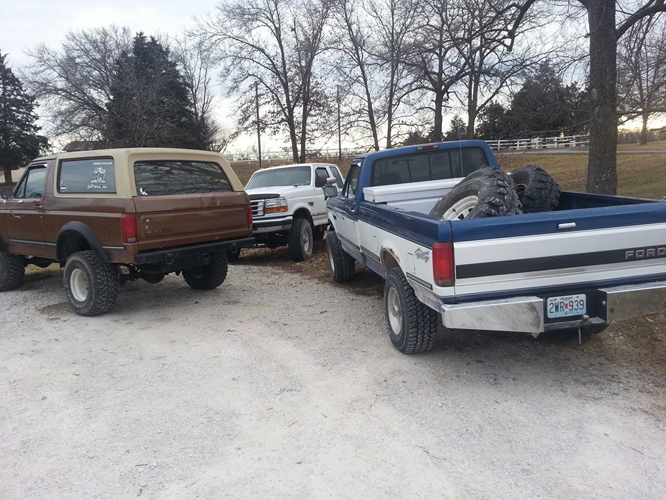 1987 Ford Bronco and two Ford pickup trucks parked on gravel lot
