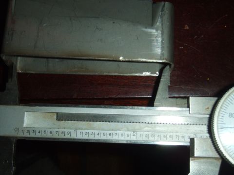 1996 Ford Bronco - A caliper is used to precisely measure the dimensions of a metal component, with a dial indicator showing the measurement.