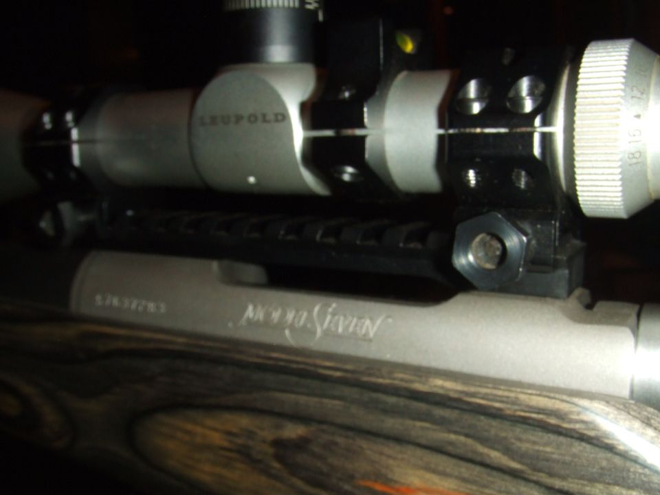 Rifle scope mounted on receiver with wooden stock. Serial number and "AK990 Seven" visible