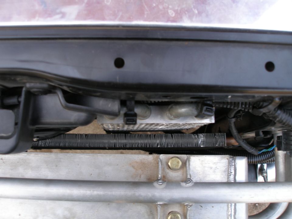 Car radiator and cooling system parts, close-up view showing metal fins and hoses