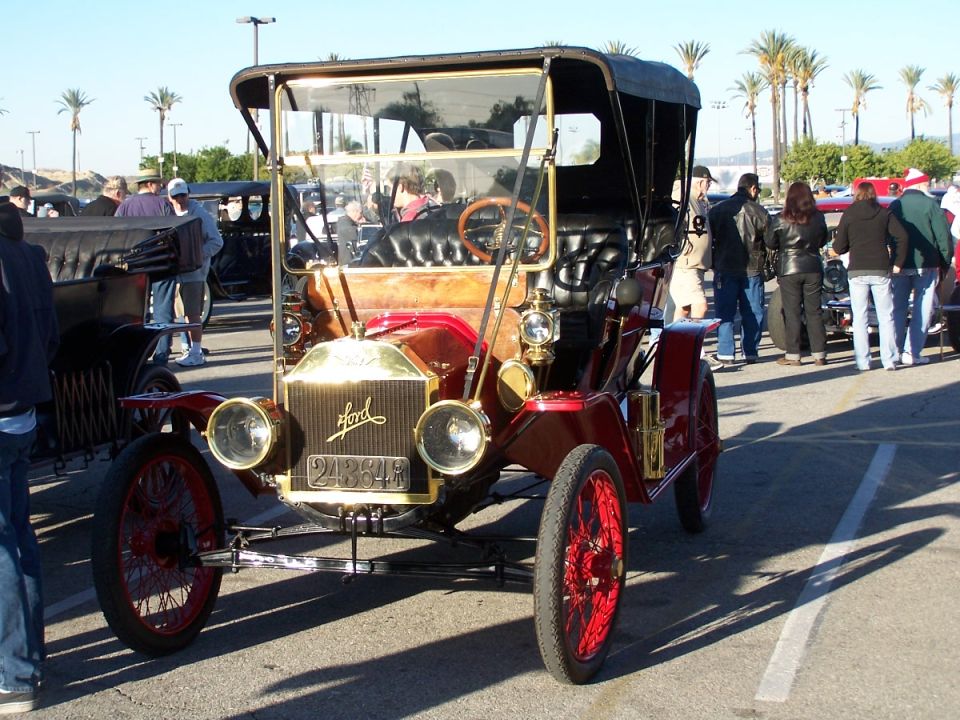 Front view of a red Ford Model T touring car with a black top and brass accents. License plate reads 23884R