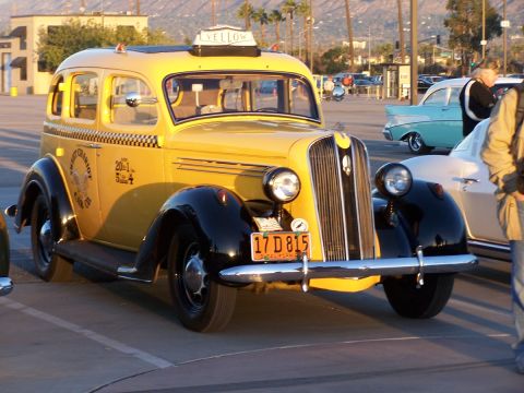 1990 Ford Bronco - Vintage yellow taxi cab with checkerboard stripe and "Yellow" sign on roof.