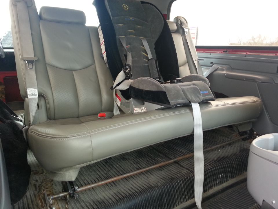 Back seat with a child car seat installed. The seats are gray leather