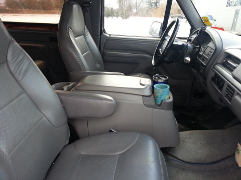 1995 Ford Bronco - Interior view of a truck, showing gray leather seats, dashboard, and center console with cup holders.