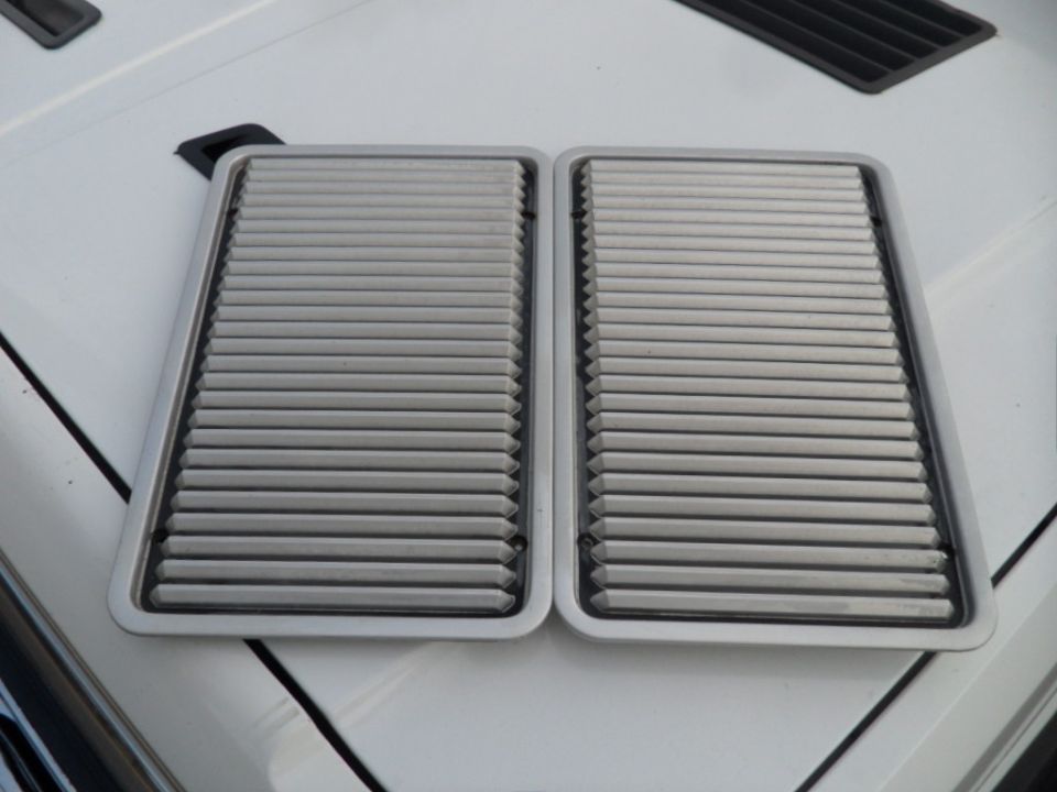 two rectangular air cleaner housings with horizontal slats on a white surface