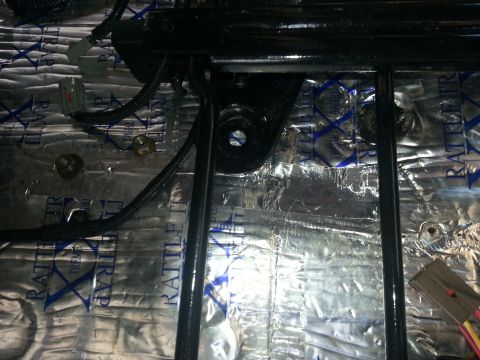 1994 Ford Bronco - Close-up view of a seat mounting bracket and wiring, with sound deadening material visible on the floor.