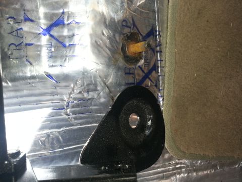 1994 Ford Bronco - A black metal bracket is attached to silver sound deadening material, likely part of a seat mounting system.