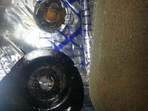 1994 Ford Bronco - Close-up view of seat mounting hardware, including a black bracket and a rusty bolt, with insulation visible.