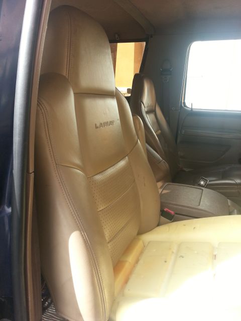 1994 Ford Bronco - The interior of a vehicle shows tan leather seats with 'Lariat' badging, and the seat cushion is visible.